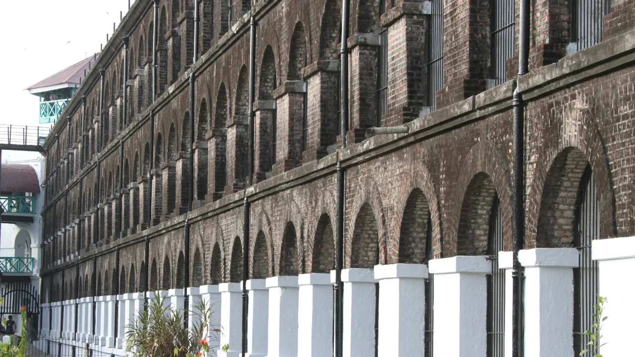 Long brick‑arched façade of the historic Cellular Jail, with whitewashed pillars at the base and watchtower in the background.