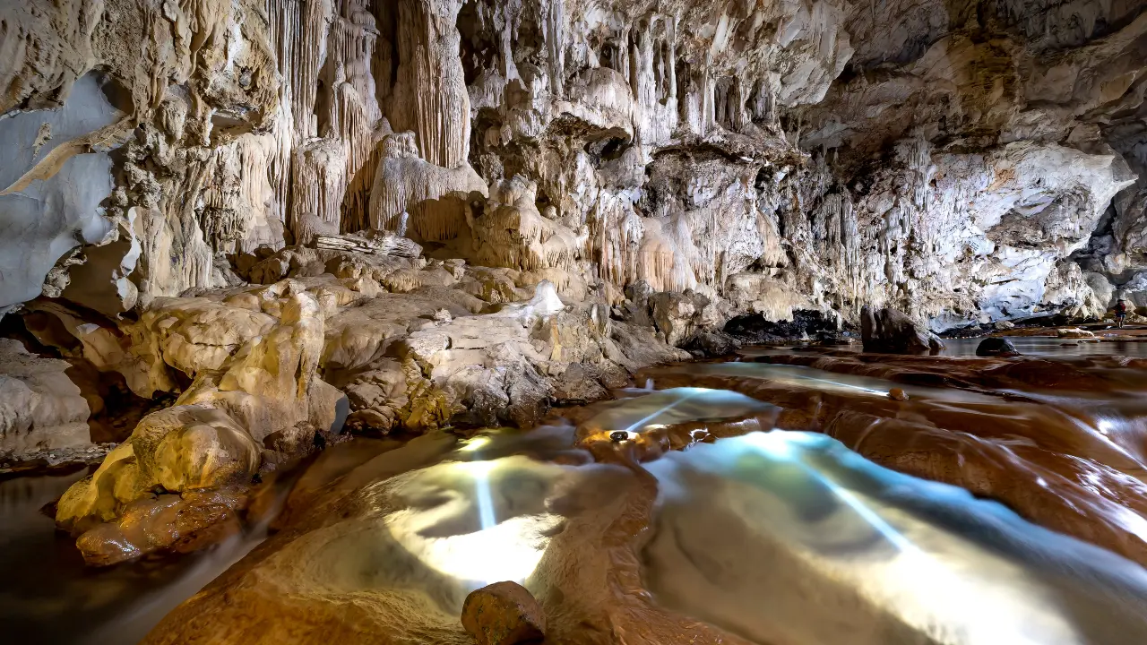 Tourists exploring natural limestone caves surrounded by dense mangroves in Baratang Island, Andaman
