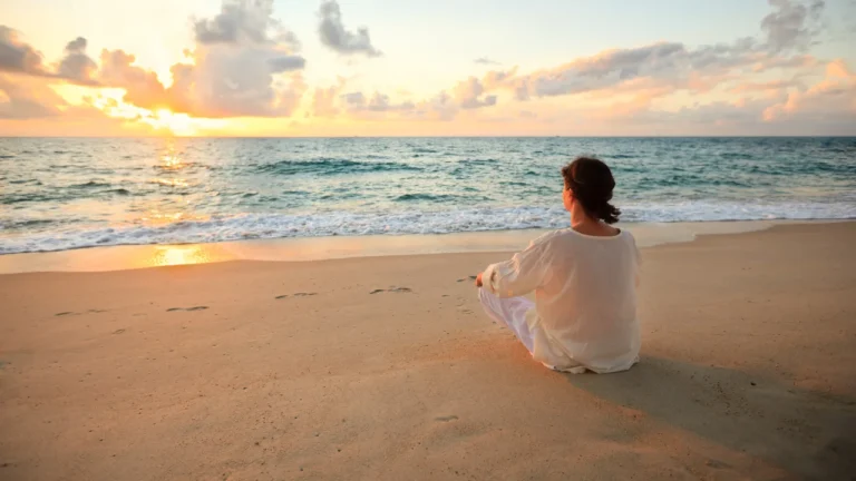 Woman meditating on a peaceful beach during sunrise in the Andaman Islands