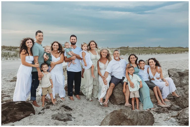 A large multigenerational family posing joyfully on a sandy beach during a luxury family vacation in Andaman, dressed in coordinated summer outfits.
